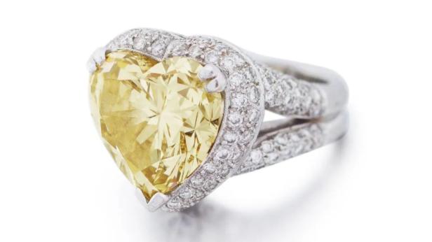 Ein Ring mit einem herzförmigen, gelben Diamanten und kleineren Diamanten rundherum.