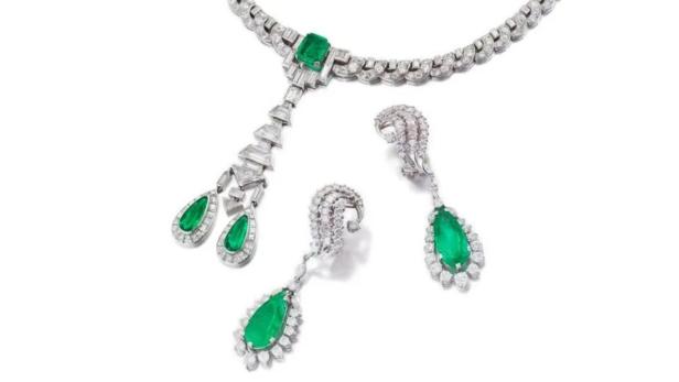 Ein smaragdgrünes Collier und Ohrringe mit Diamanten auf weißem Grund.