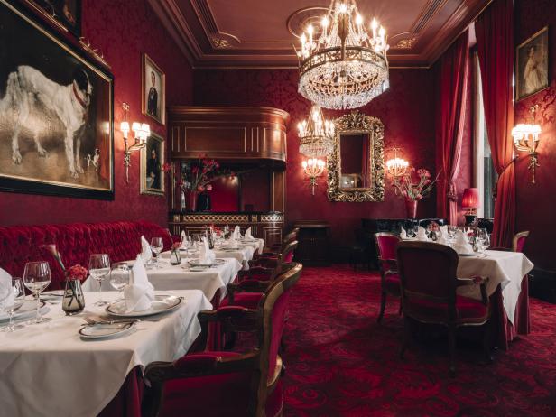 Ein Speisesaal im Hotel Sacher Wien mit roter Dekoration und elegant gedeckten Tischen.
