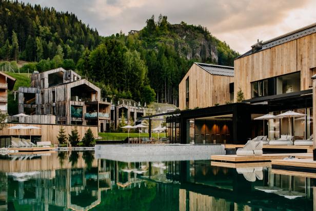 Das Naturhotel Forsthofgut spiegelt sich im smaragdgrünen Wasser.