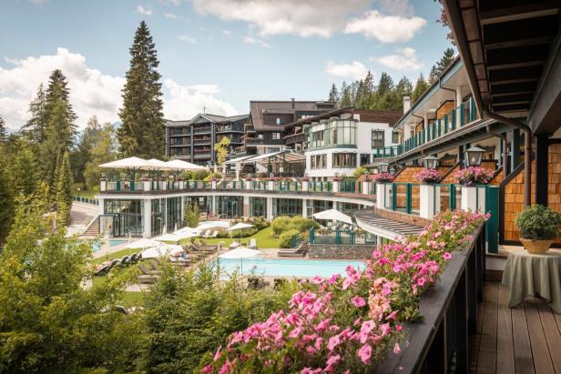 Das Alpin Resort Sacher mit Pool und blühenden Blumenkästen.