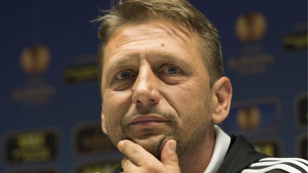 Ein Mann mit hellen Augen und Dreitagebart hält seine Hand ans Kinn.