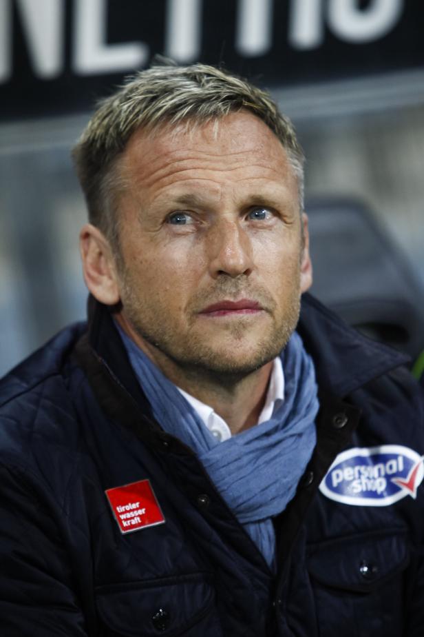 Ein Mann mit blauen Augen und einem blauen Schal blickt nachdenklich zur Seite.