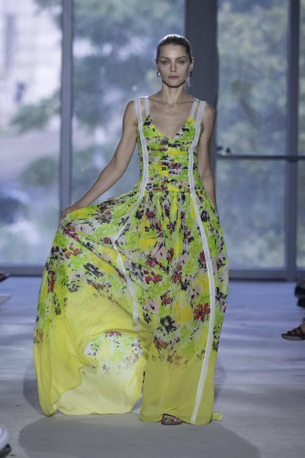 Ein Model präsentiert ein langes, blumengemustertes Kleid.