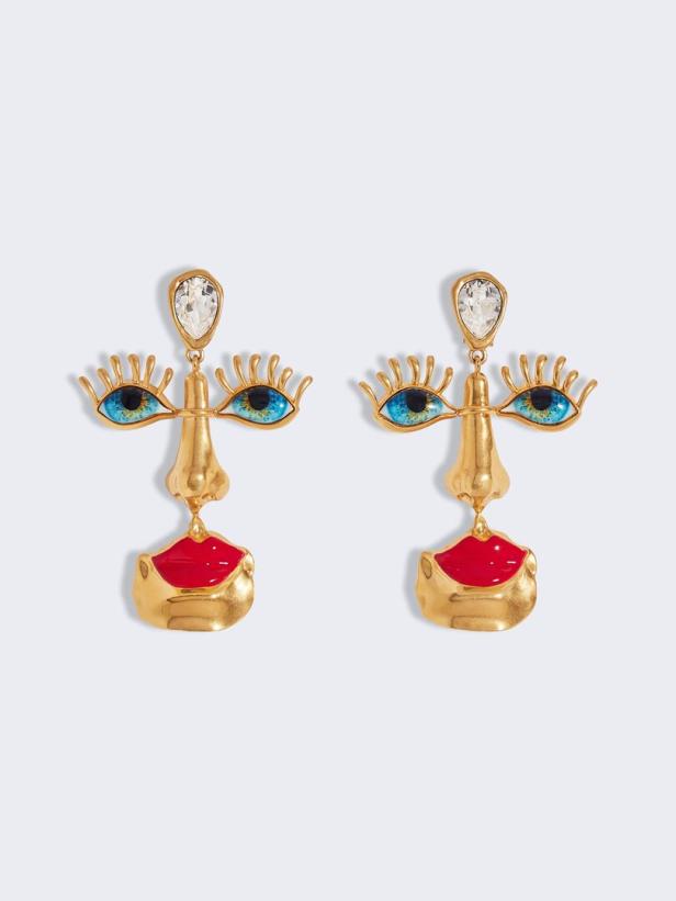 Zwei goldene Ohrringe in Form eines stilisierten Gesichts mit Augen, Nase und Lippen.