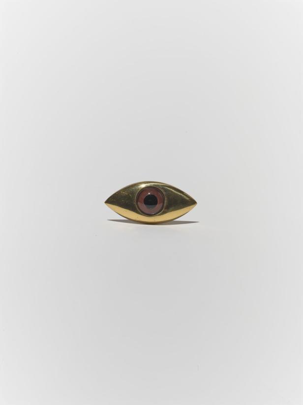 Eine goldene Brosche in Form eines Auges mit brauner Iris.