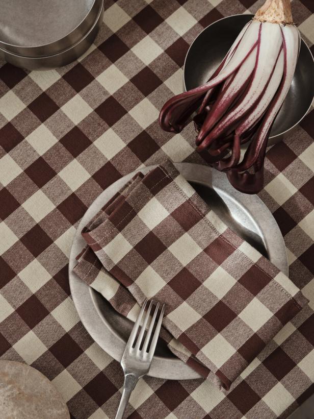 Ein gedeckter Tisch mit Radicchio, Teller, Serviette und Gabel auf einem karierten Tischtuch.