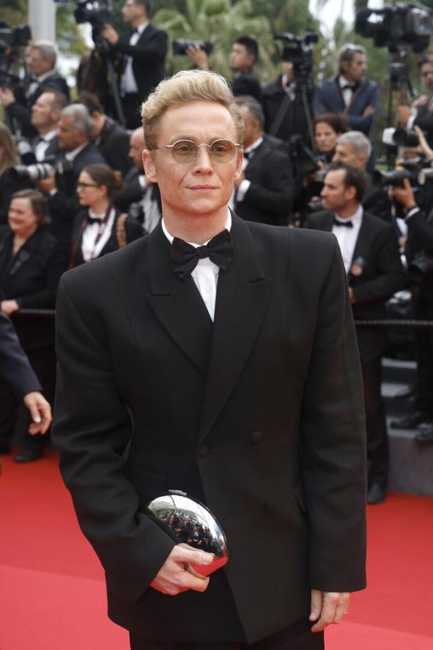 Schauspieler Joel Grey auf dem roten Teppich mit einer silbernen Clutch.