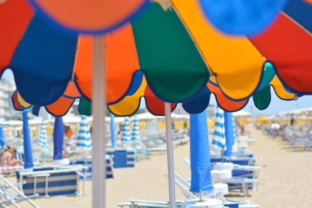 Bunte Sonnenschirme und Strandliegen am Sand-Strand