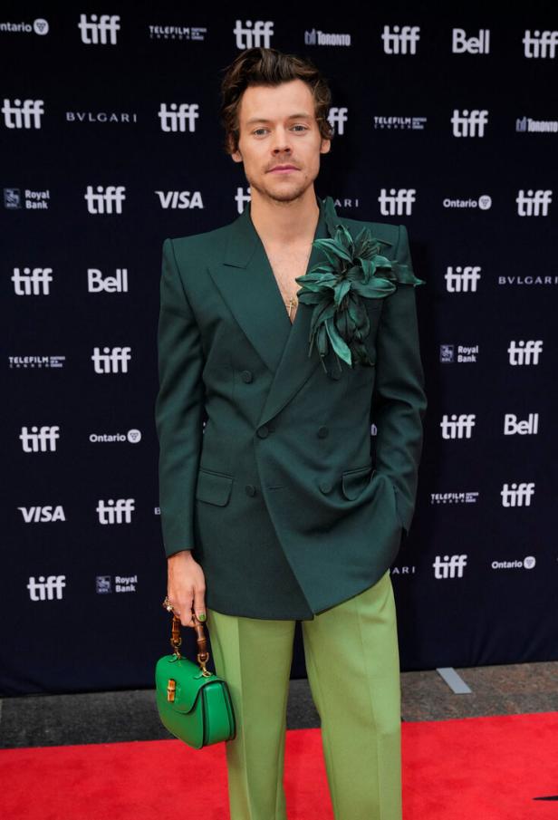 Harry Styles in einem grünen Anzug mit Blumenapplikation und grüner Handtasche auf dem TIFF.