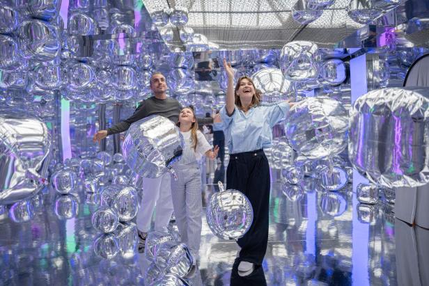 Eine Familie posiert in einer Installation mit silbernen, ballonartigen Objekten namens „Ikono“.