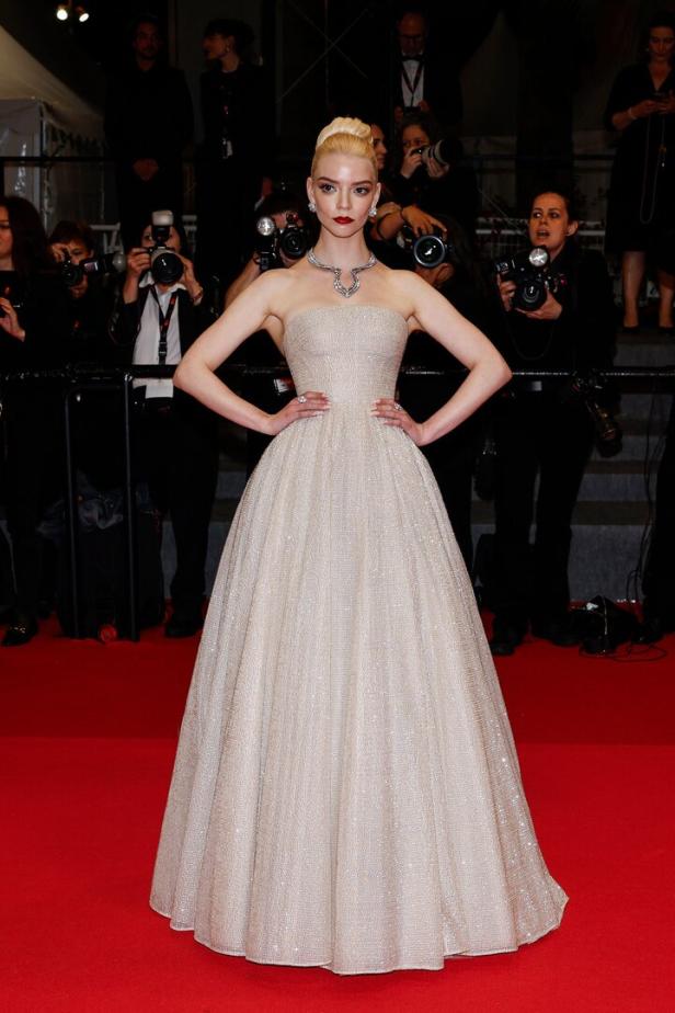 Anya Taylor-Joy posiert in einem eleganten Kleid auf einem roten Teppich vor Fotografen.