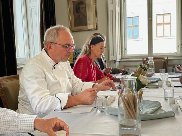 Eine Gruppe von Personen sitzt an einem Tisch und nimmt an einer Verkostung teil.