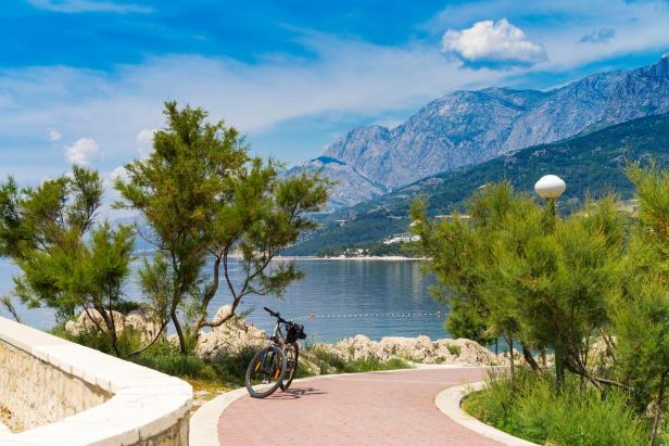Ein Fahrrad steht auf einem Weg mit Blick auf das Meer und die Berge.