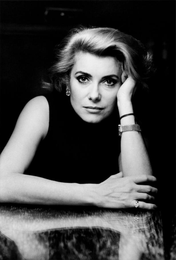 Eine Porträtaufnahme von Catherine Deneuve. Sie hat den Kopf auf ihre Hand gestützt und blickt etwas ernst drein.