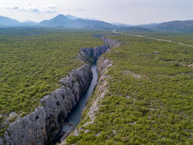 Luftaufnahme einer Schlucht mit einem Fluss, umgeben von grüner Vegetation.