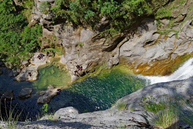 Eine Gruppe von Personen beim Canyoning in einer felsigen Schlucht mit Wasserfällen.
