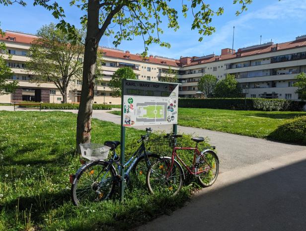 Zwei Fahrräder stehen an einem Schild des Karl-Marx-Hofs in Wien.