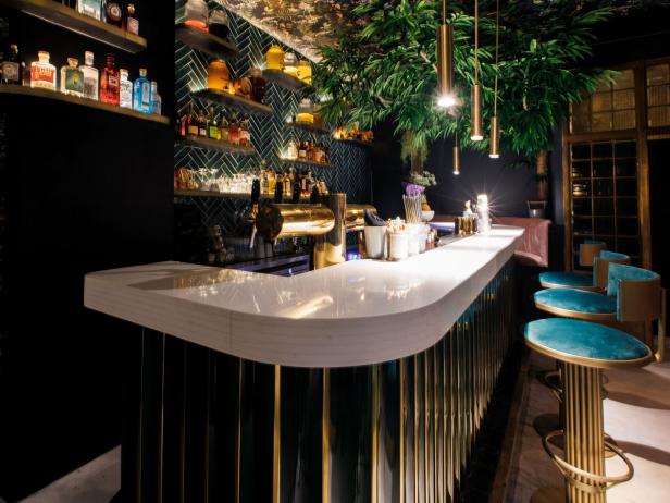 Eine Bar mit grünen und goldenen Akzenten und blauen Barhockern.
