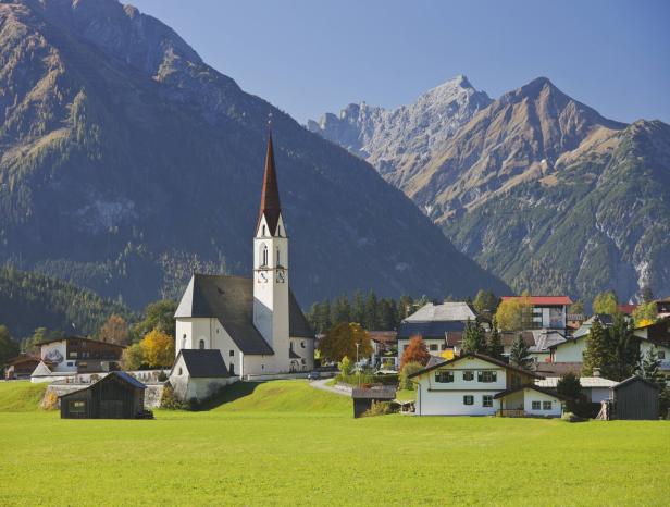 Eine Kirche in einem kleinen Dorf vor einer Bergkulisse.