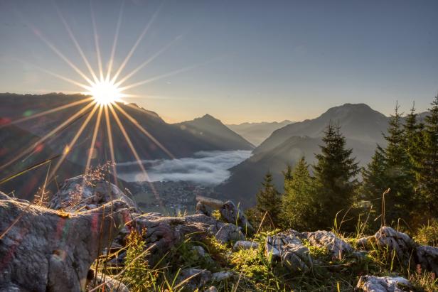 Sonnenaufgang über einer Berglandschaft mit Nebel im Tal.
