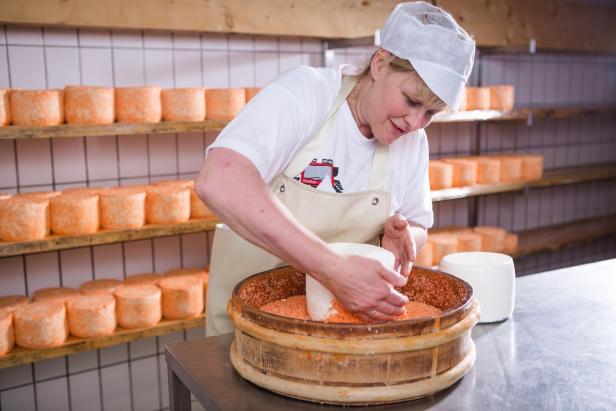 Eine Frau stellt Käse in einer Käserei her.