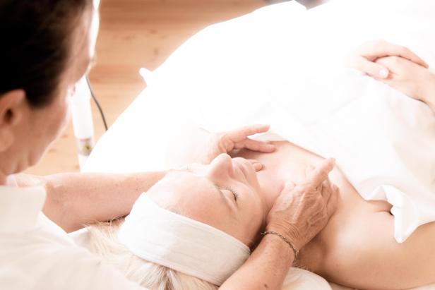 Frau auf Spa-Liege erhält ein Gesichtstreatment.