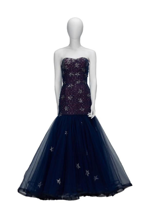 Eine Schaufensterpuppe trägt ein dunkelblaues, trägerloses Abendkleid mit silbernen Sternen.