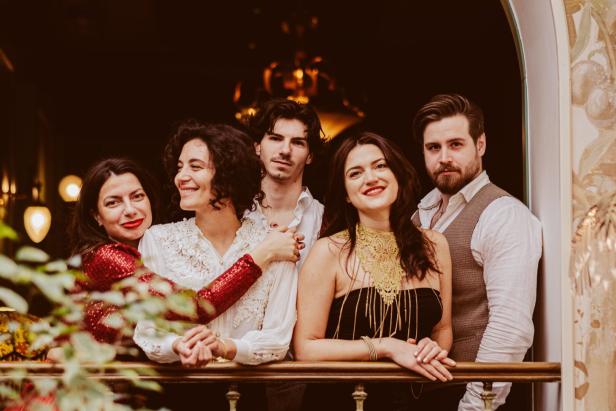 Fünf Personen posieren auf einem Balkon für ein Gruppenfoto.