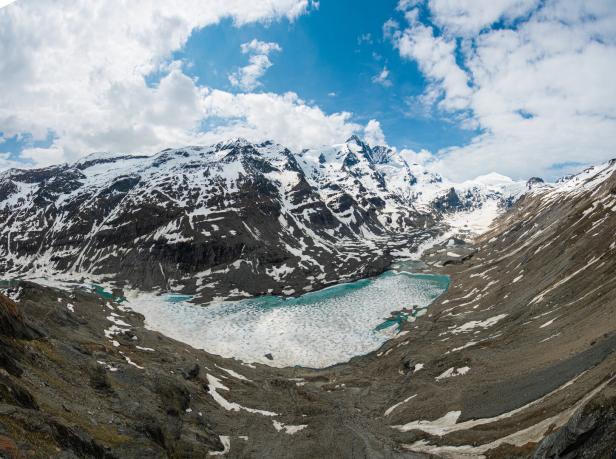 Der Großglockner Gletscher und ein teilweise gefrorener See in einer Berglandschaft.