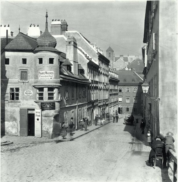 Eine historische Aufnahme der Fassziehergasse in Wien mit Passanten und Geschäften wie „Franz Wagner Passepartout“.
