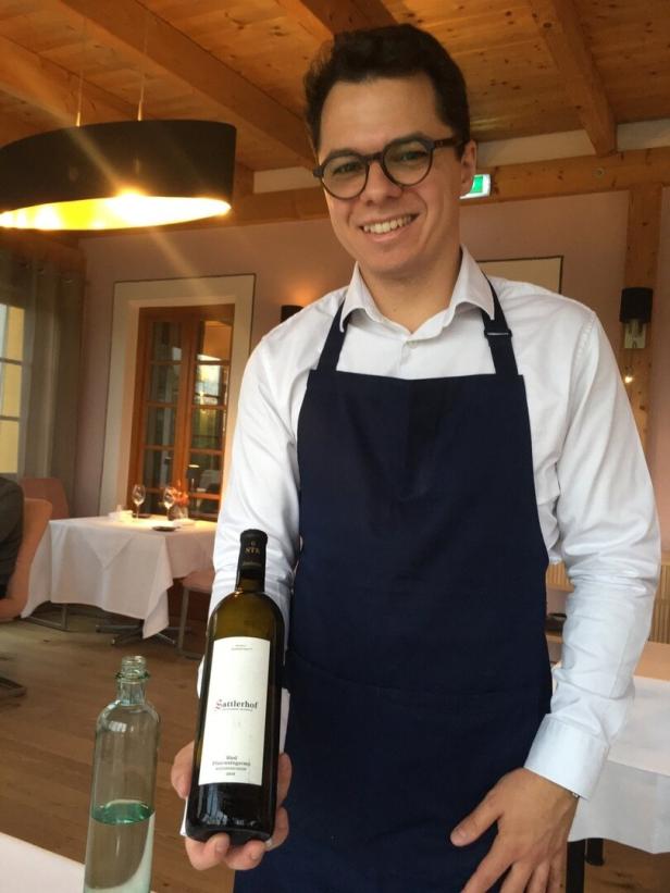 Sommelier Thomas Ferrand im Sattlerhof präsentiert eine Flasche Weißwein zum Fine Dining
