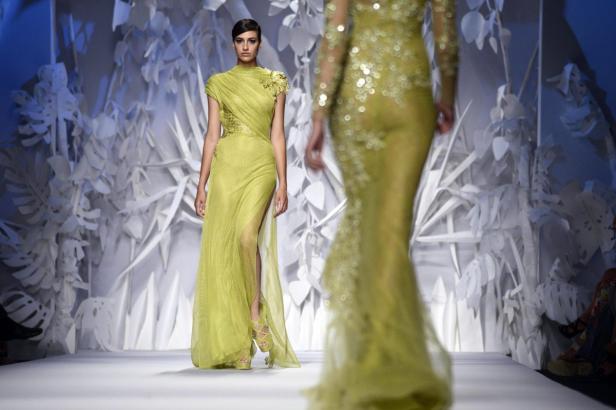 Eine Frau in einem hellgrünen, bodenlangen Kleid auf einem Laufsteg.