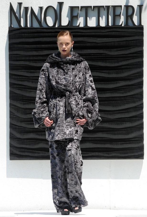 Eine Frau präsentiert ein graues Fellensemble von Nino Lettieri.