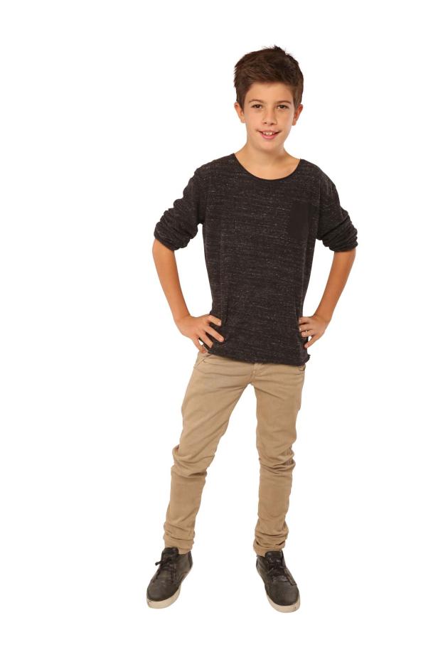 Ein junger Junge posiert selbstbewusst mit den Händen in den Hüften.