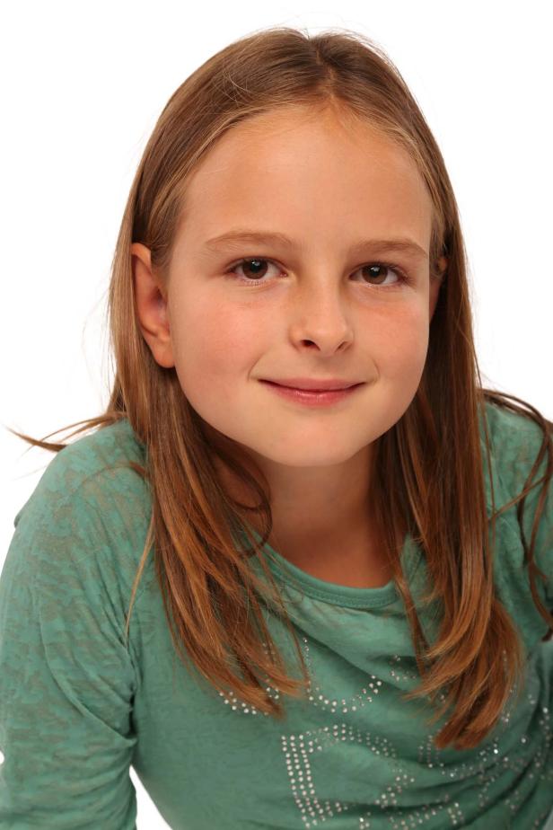 Ein junges Mädchen mit braunen Haaren und einem grünen Oberteil lächelt.