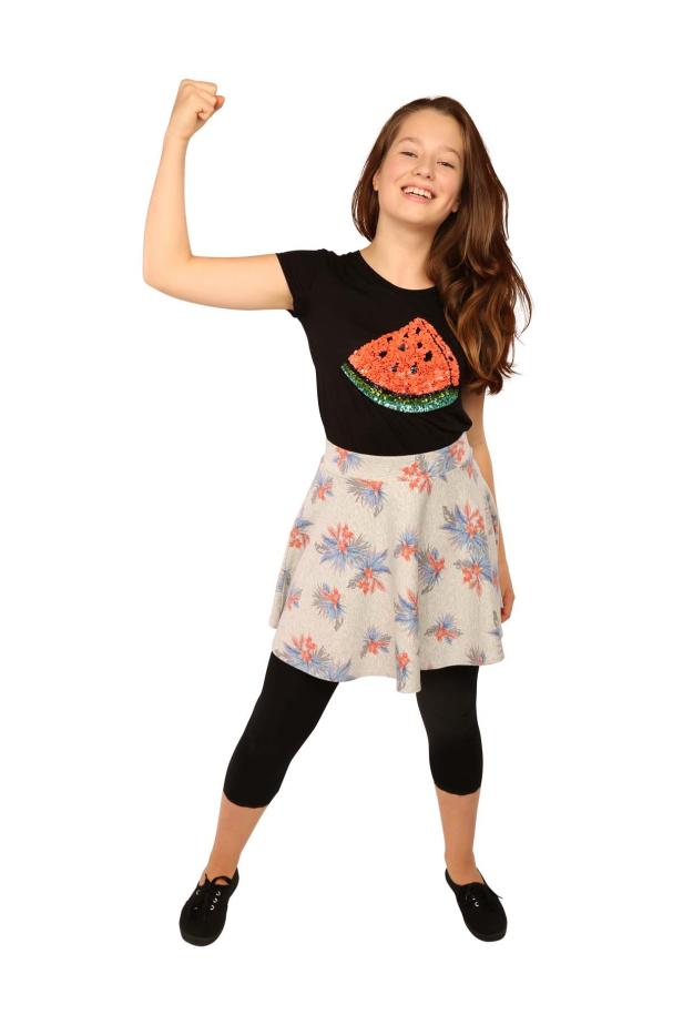 Ein junges Mädchen mit erhobenem Arm, trägt ein T-Shirt mit einer aufgenähten Wassermelone.