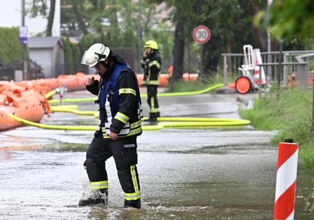 Feuerwehrmänner in Eichenau in Bayern versuchen, die Flut von der Straße fernzuhalten.