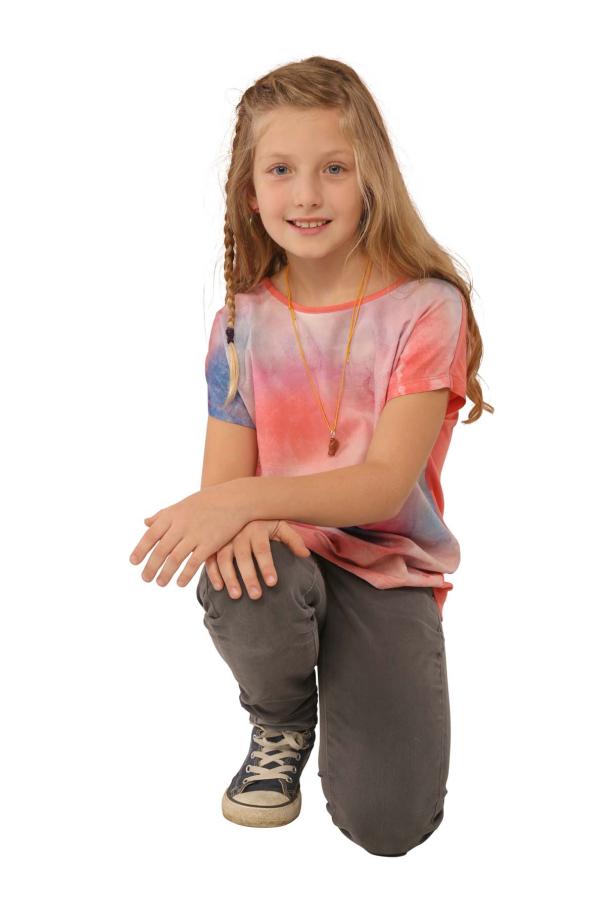 Ein junges Mädchen kniet und lächelt in die Kamera.