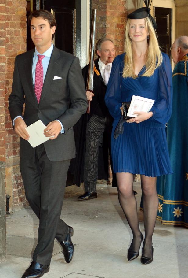 Ein Mann im Anzug und eine Frau im blauen Kleid verlassen ein Gebäude.