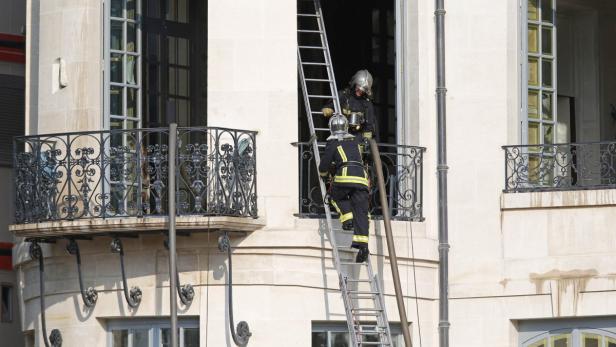 Zwei Feuerwehrleute steigen eine Leiter zu einem Gebäude hinauf.