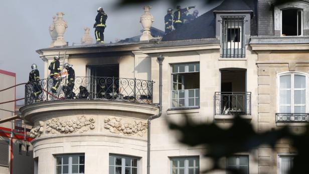 Feuerwehrleute arbeiten an einem Brand in einem Gebäude mit verzierten Balkonen.