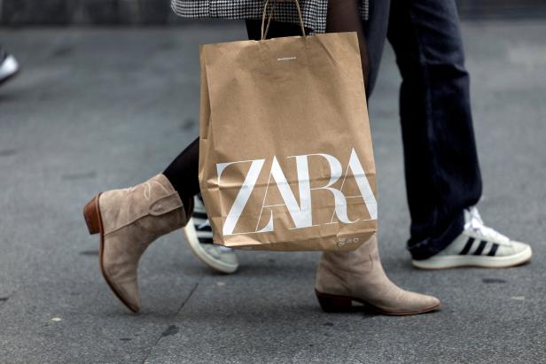 Eine Person trägt eine Zara-Einkaufstasche und Wildlederstiefel.