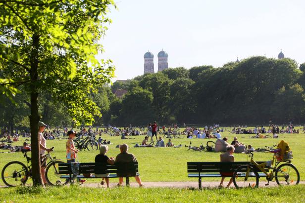 Menschen entspannen im Englischen Garten in München.