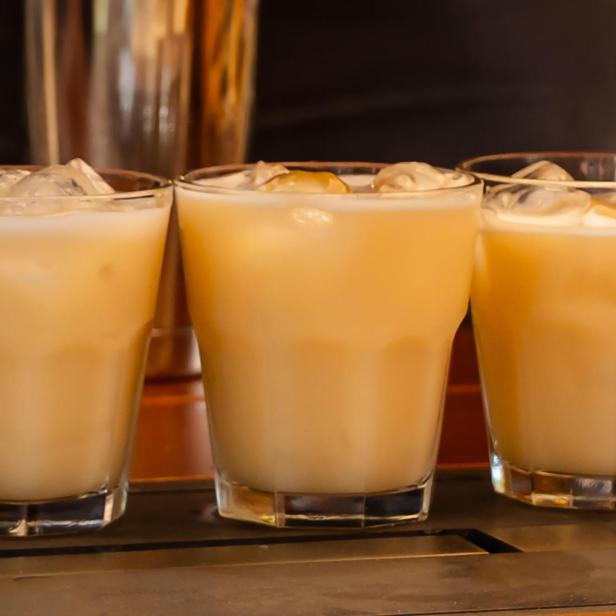 Drei Gläser mit einem hellen, eisgekühlten Getränk stehen auf einer Bar.