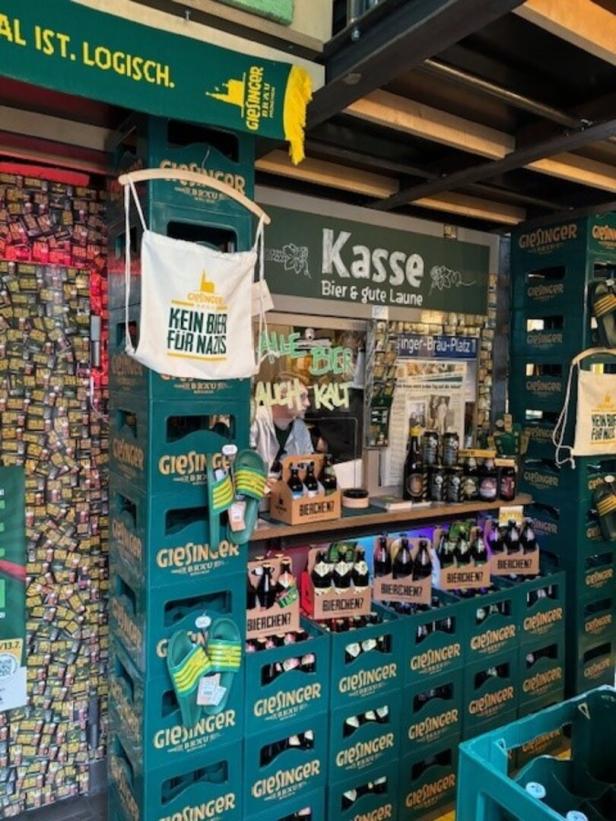 Ein Verkaufsstand mit Giesinger Bierkisten, einem Schild „Kasse“ und einem Beutel mit der Aufschrift „Kein Bier für Nazis“.