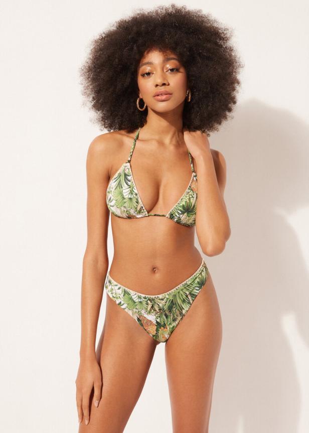 Eine Frau mit Afro trägt einen Bikini mit tropischem Muster.
