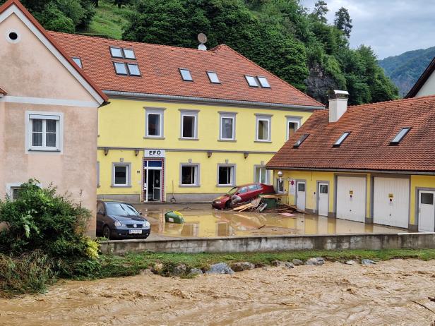 Hochwasserführender Bach vor Häusern