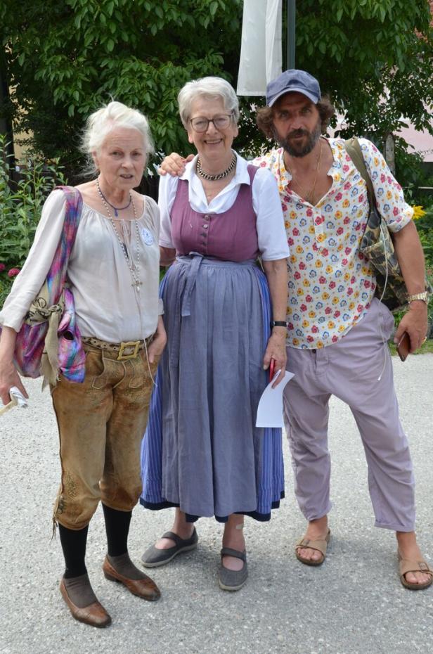 Drei Personen posieren im Freien, eine davon in Tracht.
