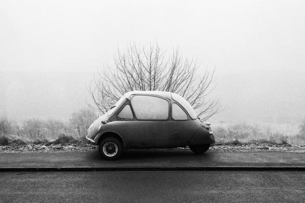 Ein mit Frost bedecktes Goggomobil steht am Straßenrand; im Hintergrund ein Baum.